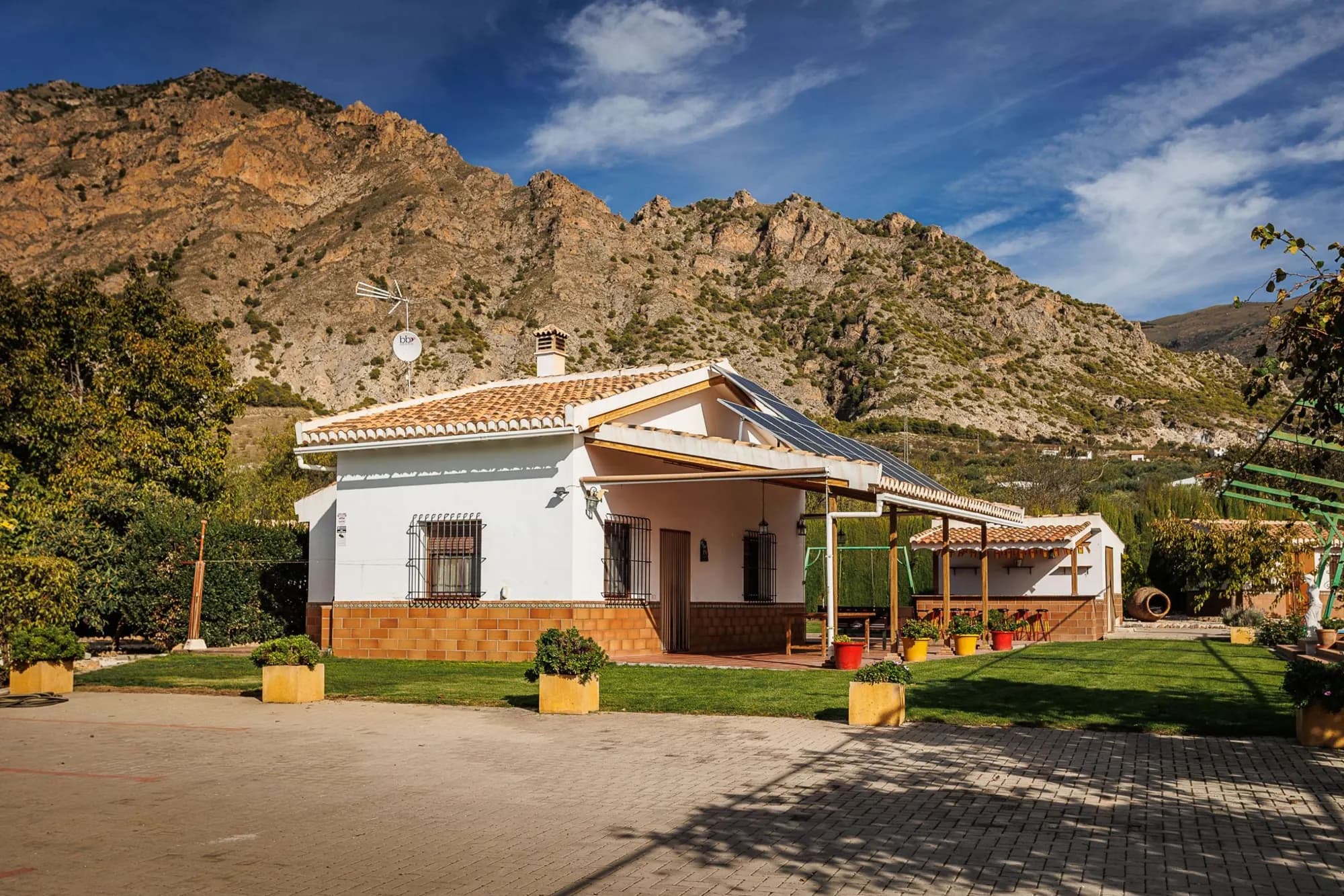 Fachada de la casa rural de Nigüelas con las montañas detrás
