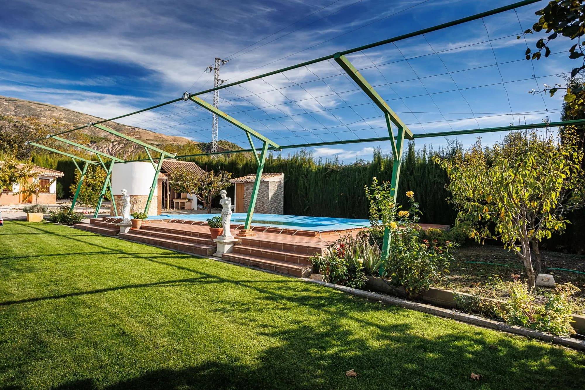 Piscina y jardín de la casa rural de Nigüelas con la sierra al fondo
